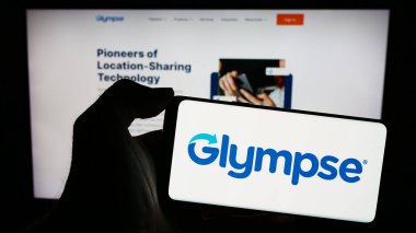 Stuttgart, Almanya - 02-24-2024: İnternet sayfası önünde üzerinde Amerikan coğrafi konum izleme şirketi Glenmpse Inc. 'in logosu bulunan cep telefonu sahibi kişi. Telefon ekranına odaklan.