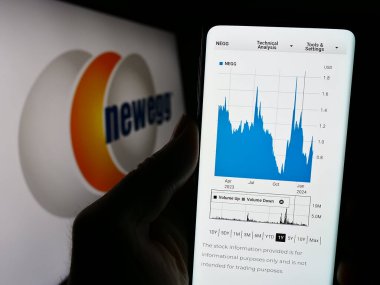 Stuttgart, Almanya - 02-24-2024: ABD 'li bilgisayar perakende şirketi Newegg Commerce Inc.' in web sitesi ile logo önünde cep telefonu tutan kişi. Telefon ekranının merkezine odaklan.