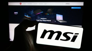 Stuttgart, Almanya - 02-24-2024: Tayvanlı Micro-Star International Co. Ltd. (MSI) şirketinin logosuna sahip cep telefonu sahibi kişi web sayfasının önünde. Telefon ekranına odaklan.
