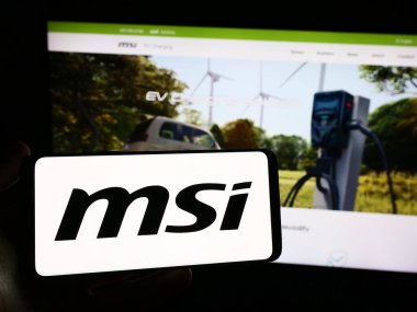 Stuttgart, Almanya - 02-24-2024: Tayvanlı Micro-Star International Co. Ltd. (MSI) şirketinin logosuna sahip akıllı telefon sahibi kişi web sitesinin önünde. Telefon ekranına odaklan.