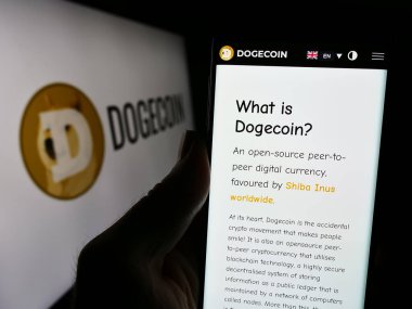 Stuttgart, Almanya - 02-26-2024: Logonun önünde şifreli para birimi Dogecoin web sayfası bulunan kişi. Telefon ekranının merkezine odaklan.