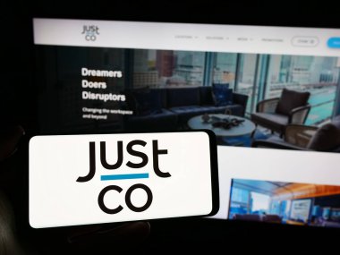 Stuttgart, Almanya - 02-26-2024: Singapurlu çalışma alanı şirketi JustCo Group 'un logosunun bulunduğu akıllı telefonu web sitesinin önünde tutan kişi. Telefon ekranına odaklan.