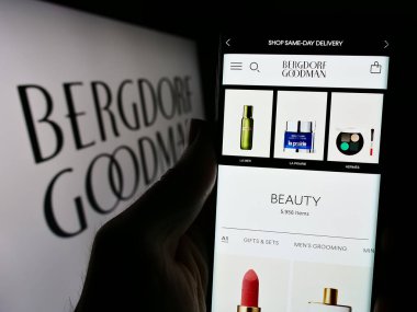 Stuttgart, Almanya - 02-26-2024: ABD 'li lüks mağaza şirketi Bergdorf Goodman Inc.' in logolu web sayfası ile cep telefonu tutan kişi. Telefon ekranının merkezine odaklan.