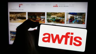 Stuttgart, Almanya - 02-26-2024: Hintli işyeri şirketi Awfis Space Solutions Limited 'in logosuna sahip cep telefonu sahibi kişi web sayfasının önünde. Telefon ekranına odaklan.