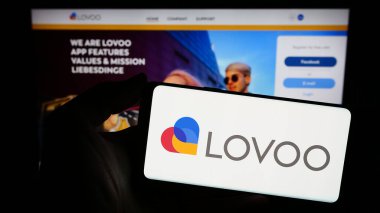 Stuttgart, Almanya - 02-26-2024: İnternet sitesi önünde Alman online flört platformu LOVOO 'nun logosuna sahip kişi. Telefon ekranına odaklan.
