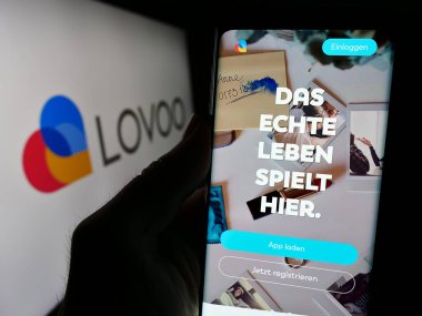 Stuttgart, Almanya - 02-26-2024: Logo önünde Alman online flört platformu LOVOO 'nun web sayfası ile cep telefonu tutan kişi. Telefon ekranının merkezine odaklan.