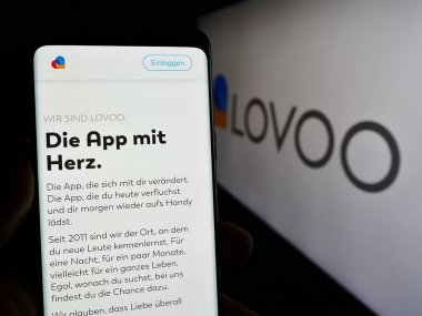 Stuttgart, Almanya - 02-26-2024: Logo önünde Alman online flört platformu LOVOO 'nun web sayfası ile cep telefonu tutan kişi. Telefon ekranının merkezine odaklan.