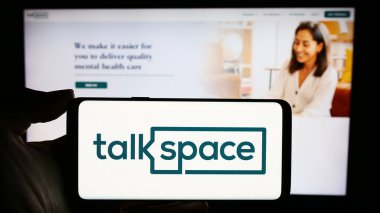 Stuttgart, Almanya - 02-29-2024: ABD 'li online psikoterapi şirketi Talkspace Inc.' in logosuyla cep telefonu tutan kişi iş sayfasının önünde. Telefon ekranına odaklan.