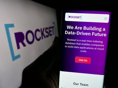 Stuttgart, Almanya - 02-29-2024: ABD analitik veritabanı şirketi Rockset Inc. 'in web sayfası ile logo önünde cep telefonu tutan kişi. Telefon ekranının merkezine odaklan.