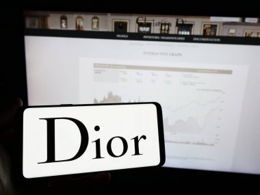 Stuttgart, Almanya - 03-01-2024: Fransız lüks moda şirketi Christian Dior SE 'nin logosunun bulunduğu cep telefonu sahibi kişi iş sayfasının önünde. Telefon ekranına odaklan.
