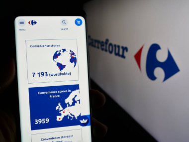 Stuttgart, Almanya - 03-01-2024: Fransız perakende şirketi Carrefour S.A. 'nın web sayfası ile akıllı telefon sahibi kişi iş logosu önünde. Telefon ekranının merkezine odaklan.