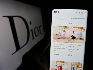 Stuttgart, Almanya - 03-01-2024: Fransız lüks moda şirketi Christian Dior SE 'nin internet sayfası ile logo önünde cep telefonu tutan kişi. Telefon ekranının merkezine odaklan.