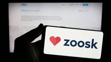 Stuttgart, Germany - 03-01-2024: Person holding smartphone with logo of online dating platform company Zoosk Inc. in front of website. Focus on phone display. clipart