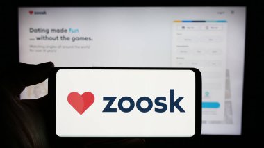 Stuttgart, Almanya - 03-01-2024: İnternet üzerinden randevu platformu şirketi Zoosk Inc. 'in logosuyla cep telefonu tutan kişi iş sayfasının önünde. Telefon ekranına odaklan.