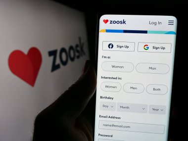 Stuttgart, Almanya - 03-01-2024: İnternet üzerinden randevu platformu şirketi Zoosk Inc. 'in logosuyla cep telefonu tutan kişi iş sayfasının önünde. Telefon ekranına odaklan.