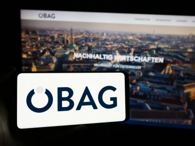 Stuttgart, Almanya - 03-14-2024: Avusturyalı Osterreichische Beteiligungs AG (BAG) şirketinin logosunun bulunduğu cep telefonu sahibi kişi web sayfasının önünde. Telefon ekranına odaklan.