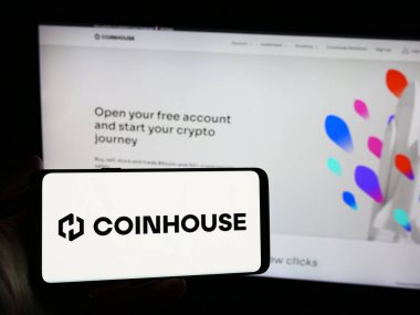 Stuttgart, Almanya - 03-14-2024: İnternet sitesinin önünde üzerinde Fransız kripto yatırım şirketi Coinhouse SAS logosu olan akıllı telefon tutan kişi. Telefon ekranına odaklan.