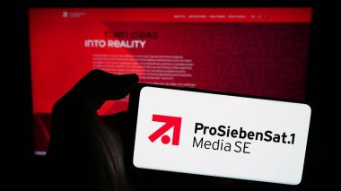 Stuttgart, Germany - 03-15-2024: Person holding smartphone with logo of German television company ProSiebenSat.1 Media SE in front of website. Focus on phone display. clipart