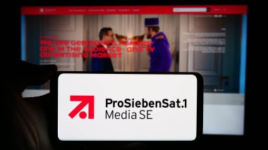 Stuttgart, Germany - 03-15-2024: Person holding cellphone with logo of German television company ProSiebenSat.1 Media SE in front of business webpage. Focus on phone display. clipart