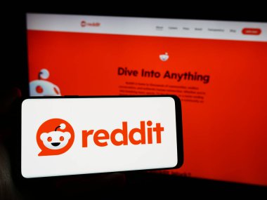 Stuttgart, Almanya - 03-15-2024: Amerikan sosyal medya şirketi Reddit Inc. 'in logosuna sahip cep telefonu sahibi kişi iş sayfasının önünde. Telefon ekranına odaklan.