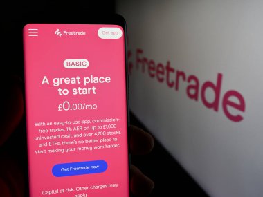 Stuttgart, Germany - 03-15-2024: Person holding cellphone with web page of British fintech company Freetrade Ltd. in front of business logo. Focus on center of phone display. clipart