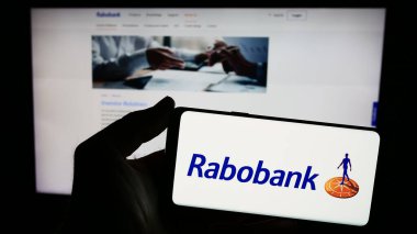 Stuttgart, Almanya - 03-16-2024: Hollandalı bankacılık şirketi Cooperatieve Rabobank U.A. 'nın logosunu taşıyan kişi İnternet sitesinin önünde. Telefon ekranına odaklan.