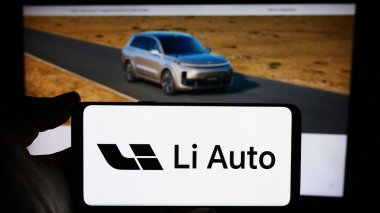 Stuttgart, Almanya - 03-16-2024: Çinli elektrikli araç şirketi Li Auto Inc. 'in logosunu taşıyan cep telefonu sahibi kişi iş sayfasının önünde. Telefon ekranına odaklan.