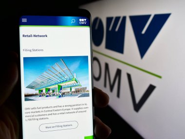 Stuttgart, Almanya - 03-16-2024: Avusturyalı petrol ve gaz şirketi OMV Aktiengesellschaft 'ın logolu web sayfası ile cep telefonu tutan kişi. Telefon ekranının merkezine odaklan.