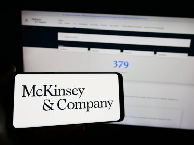 Stuttgart, Almanya - 03-16-2024: ABD 'li danışmanlık şirketi McKinsey and Company' nin logosuna sahip akıllı telefon sahibi kişi web sitesi önünde. Telefon ekranına odaklan.