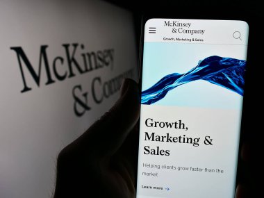 Stuttgart, Almanya - 03-16-2024: ABD 'li danışmanlık şirketi McKinsey and Company' nin logo önündeki web sayfası ile cep telefonu tutan kişi. Telefon ekranının merkezine odaklan.