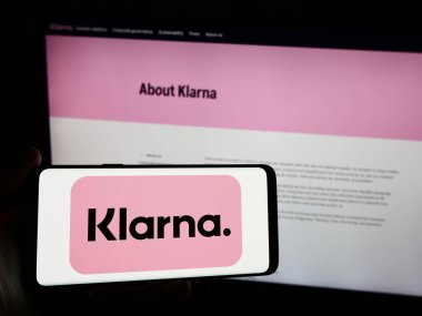 Stuttgart, Almanya - 03-16-2024: İsveçli fintech şirketi Klarna Bank AB 'nin logosuna sahip akıllı telefon sahibi kişi web sitesinin önünde. Telefon ekranına odaklan.