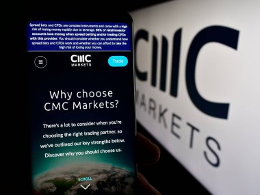 Stuttgart, Almanya - 03-16-2024: İngiliz finans hizmetleri şirketi CMC Markets plc 'ın web sayfası ile logo önünde cep telefonu tutan kişi. Telefon ekranının merkezine odaklan.