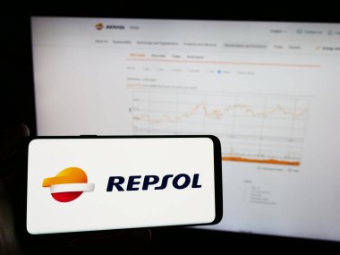 Stuttgart, Almanya - 03-16-2024: İspanyol petrol şirketi Repsol SA 'nın logosunun bulunduğu cep telefonu sahibi kişi iş sayfasının önünde. Telefon ekranına odaklan.