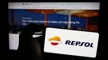 Stuttgart, Almanya - 03-16-2024: İspanyol petrol şirketi Repsol S.A. 'nın logosuna sahip akıllı telefon sahibi kişi web sitesinin önünde. Telefon ekranına odaklan.