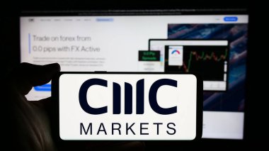 Stuttgart, Almanya - 03-16-2024: İngiliz finans hizmetleri şirketi CMC Markets plc 'ın logosuyla cep telefonu sahibi kişi iş sayfasının önünde. Telefon ekranına odaklan.