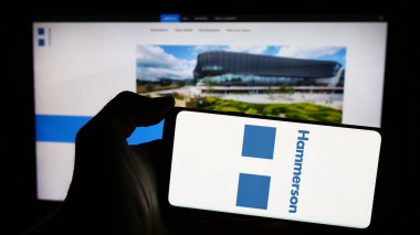 Stuttgart, Almanya - 03-16-2024: İngiliz emlak şirketi Hammerson plc 'nin logosuyla cep telefonu sahibi kişi iş sayfasının önünde. Telefon ekranına odaklan.