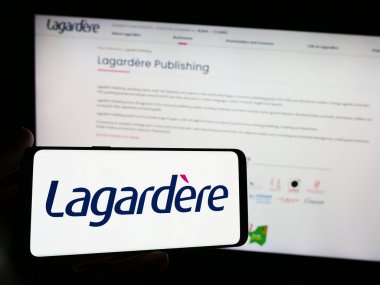 Stuttgart, Almanya - 03-17-2024: Fransız yayıncılık ve perakende şirketi Lagardere S.A. 'nın logosuna sahip akıllı telefon sahibi kişi web sitesi önünde. Telefon ekranına odaklan.