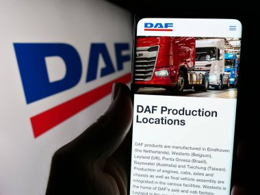 Stuttgart, Almanya - 03-17-2024: Hollandalı kamyon üreticisi DAF Trucks NV 'nin web sayfası ile logo önünde cep telefonu tutan kişi. Telefon ekranının merkezine odaklan.