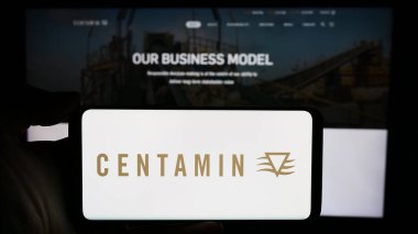 Stuttgart, Almanya - 03-17-2024: Üzerinde altın madenciliği şirketi Centamin plc logosu bulunan cep telefonu sahibi kişi iş sayfasının önünde. Telefon ekranına odaklan.
