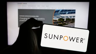 Stuttgart, Almanya - 03-17-2024: Web sayfasının önünde Amerikan fotovoltaik şirketi SunPower Corporation 'ın logosu olan cep telefonu sahibi kişi. Telefon ekranına odaklan.