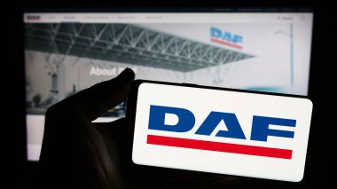 Stuttgart, Almanya - 03-17-2024: Hollandalı kamyon üreticisi DAF Trucks N.V. 'nin logosuna sahip akıllı telefon sahibi kişi web sitesinin önünde. Telefon ekranına odaklan.