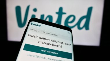 Stuttgart, Almanya - 03-17-2024: İnternet üzerinden ikinci el pazarlama şirketi Vinted 'in web sitesi ile birlikte iş logosu önünde cep telefonu. Telefon ekranının sol üst kısmına odaklan.