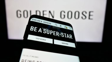 Stuttgart, Almanya - 03-05-2024: İtalyan spor ayakkabı şirketi Golden Goose S.P.A. 'nın web sitesi ile birlikte iş logosu önünde cep telefonu. Telefon ekranının sol üst kısmına odaklan.
