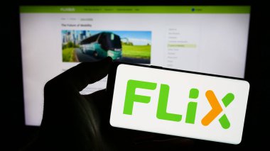 Stuttgart, Almanya - 03-05-2024: Alman taşımacılık şirketi Flix SE 'nin logosunun bulunduğu cep telefonu sahibi kişi iş sayfasının önünde. Telefon ekranına odaklan.