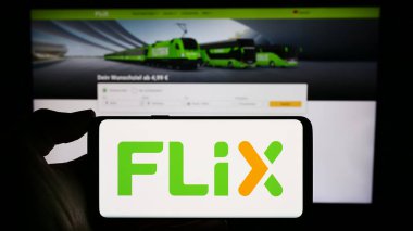 Stuttgart, Almanya - 03-05-2024: Alman taşımacılık şirketi Flix SE 'nin logosuyla cep telefonu sahibi kişi iş sayfasının önünde. Telefon ekranına odaklan.