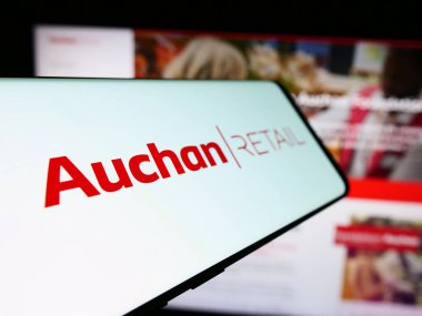 Stuttgart, Almanya - 03-05-2024: Fransız firması Auchan Retail International SA 'nın logosuna sahip akıllı telefon işletme web sitesi önünde. Telefon ekranının soluna odaklan.