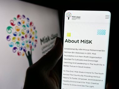 Stuttgart, Almanya - 03-05-2024: Suudi Arabistan organizasyonu MiSK Vakfı 'nın logo önündeki web sayfası ile cep telefonu tutan kişi. Telefon ekranının merkezine odaklan.