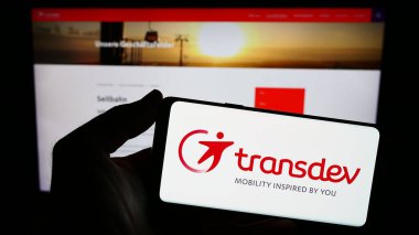 Stuttgart, Almanya - 03-05-2024: İnternet sitesi önünde Alman toplu taşıma şirketi Transdev GmbH 'nin logosuna sahip kişi. Telefon ekranına odaklan.