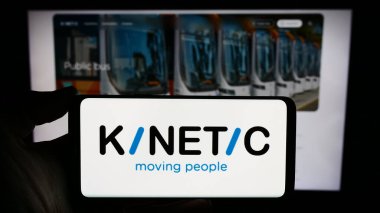 Stuttgart, Germany - 03-06-2024: Person holding smartphone with logo of Australian mobility company Kinetic Group in front of website. Focus on phone display. clipart