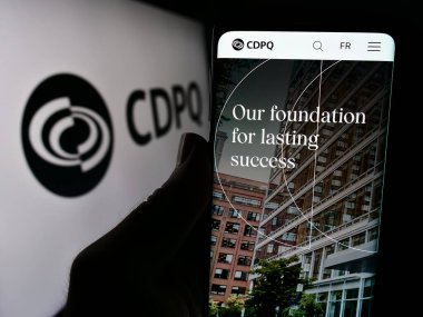 Stuttgart, Almanya - 03-06-2024: Caisse de Depot et Placement du Quebec (CDPQ) sitesinin logo önünde cep telefonu tutan kişi. Telefon ekranının merkezine odaklan.